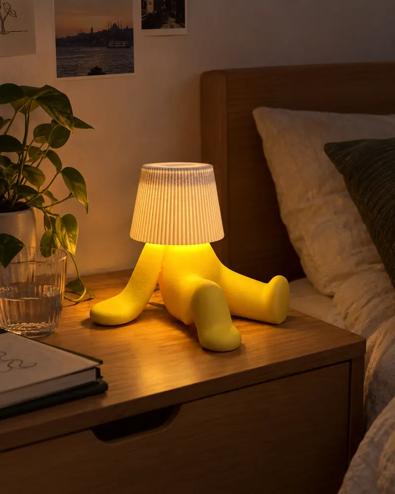 Yellow figure-shaped table lamp on a bedside table
